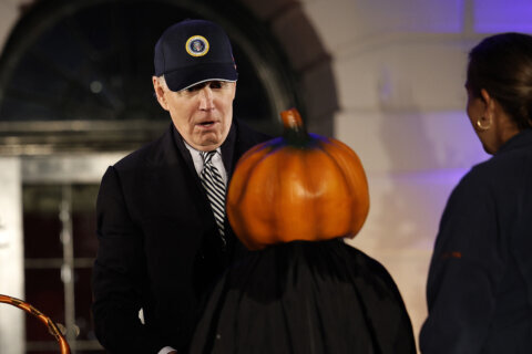 Joe Biden makes a fearful face when faced with a child dressed with on a pumpkin head