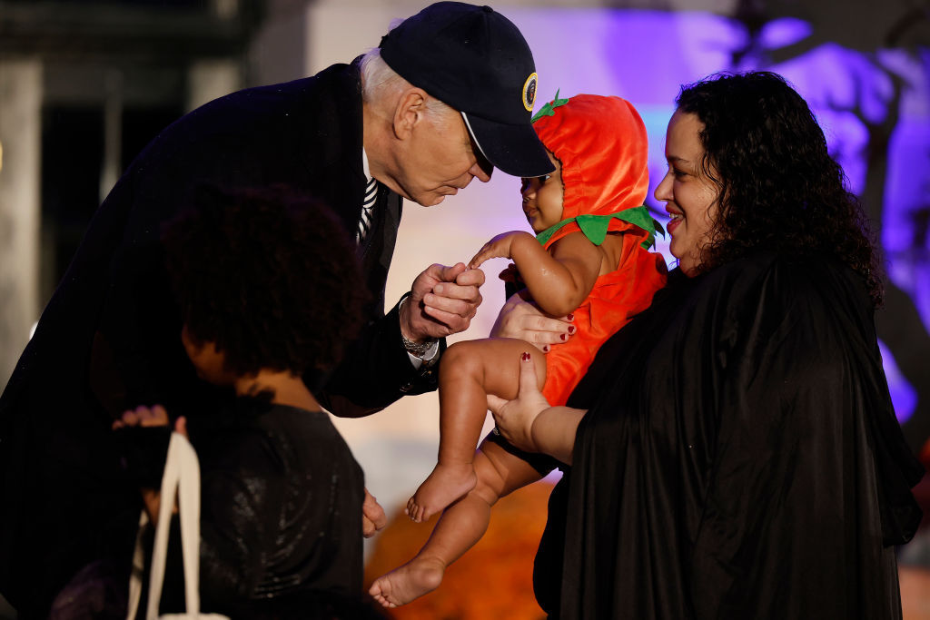 A baby dressed as a pumpkin is greeted by Joe Biden