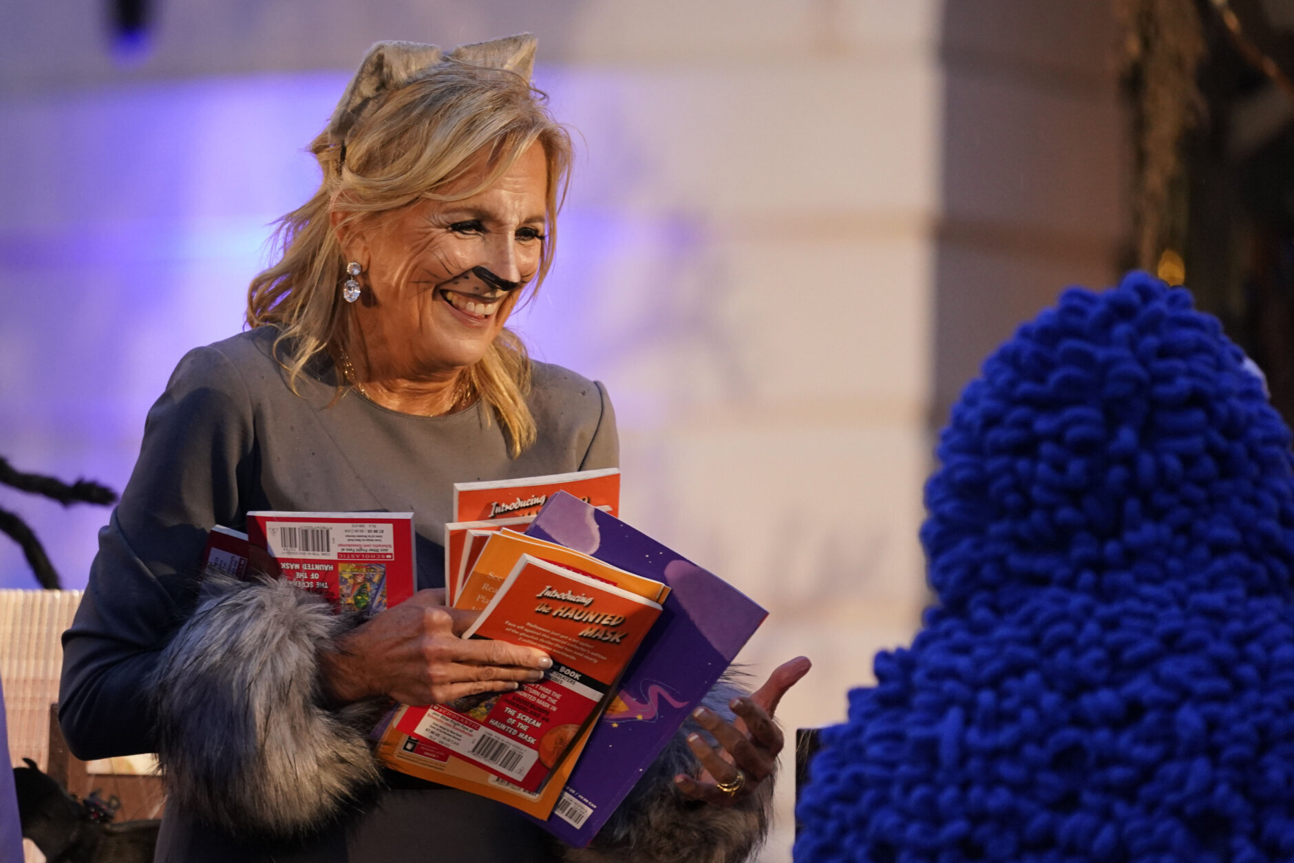 Arms full of books, First Lady Jill Biden greets trick-or-treaters