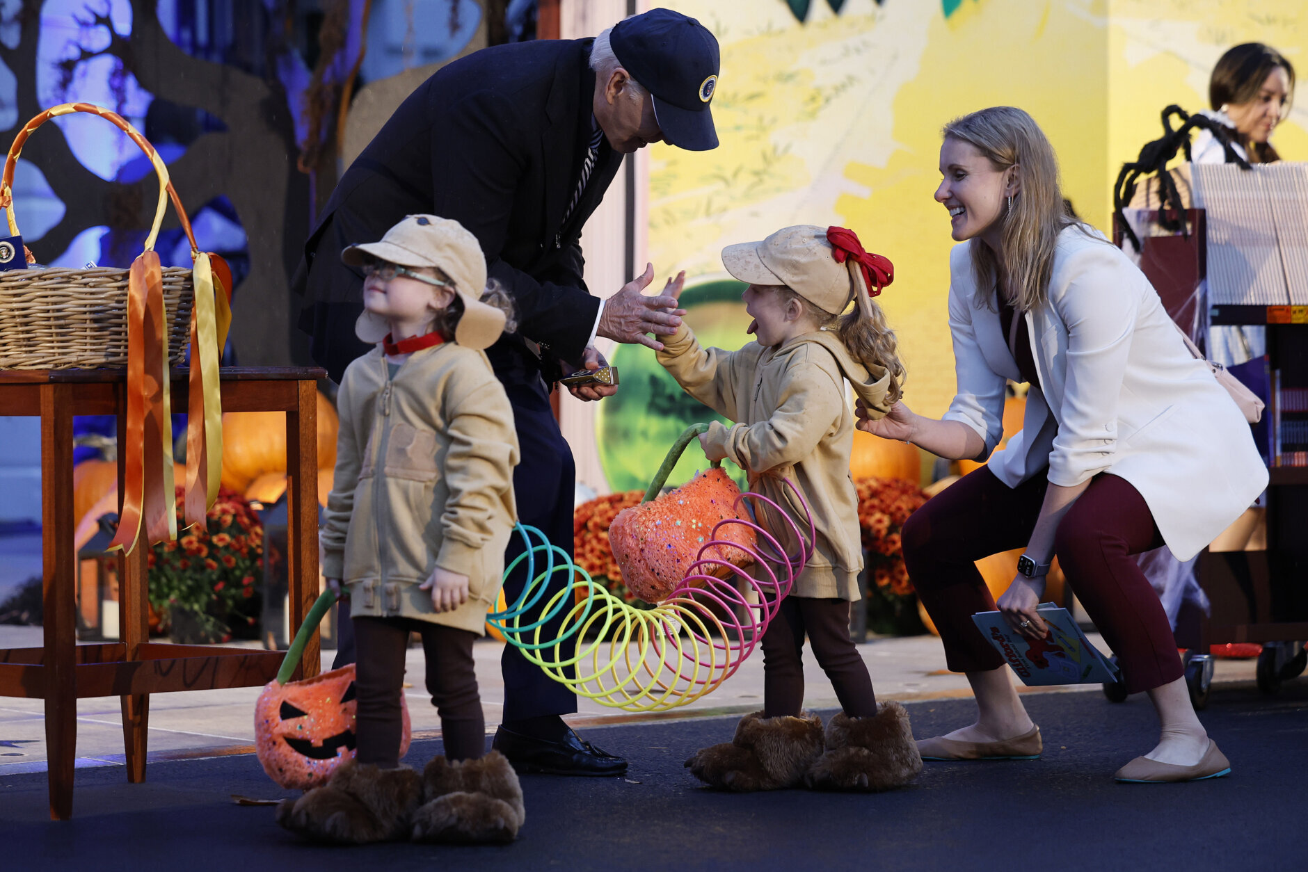 Two small kids have their costumes connected by a large slinky