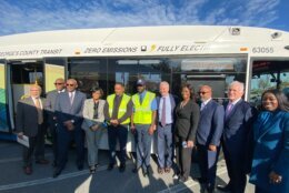 Officials stand in from of an electric bus