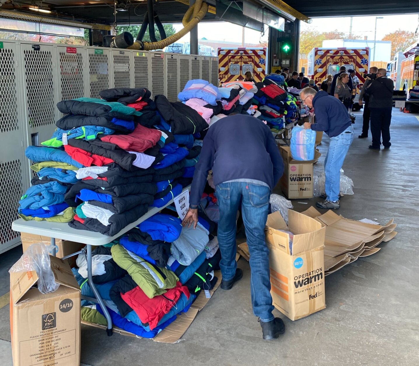 People sort through piles of coats stacked both on and below tables