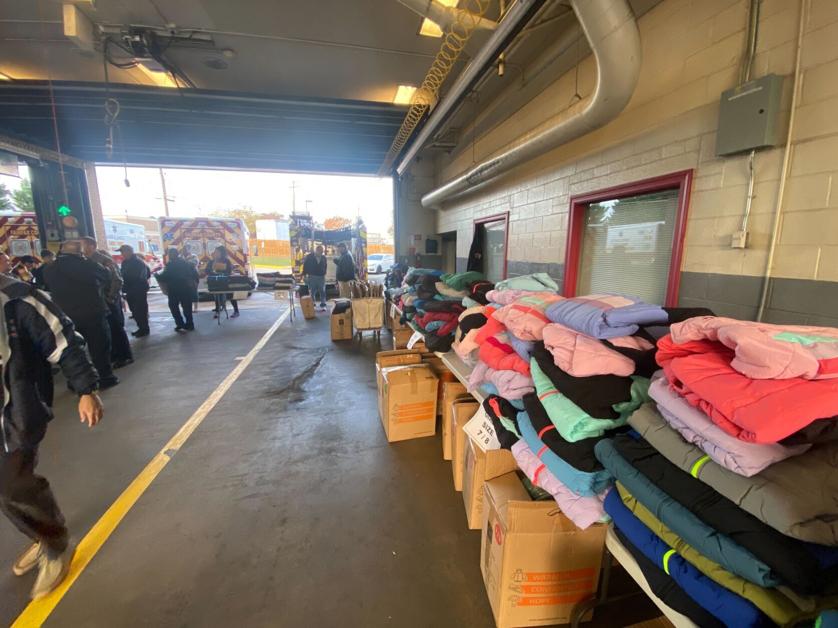 Tall piles of coats are stacked on tables in the fire station