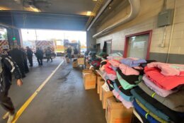 Tall piles of coats are stacked on tables in the fire station