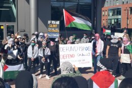 A crowd of students with signs and a Palestinian flag.