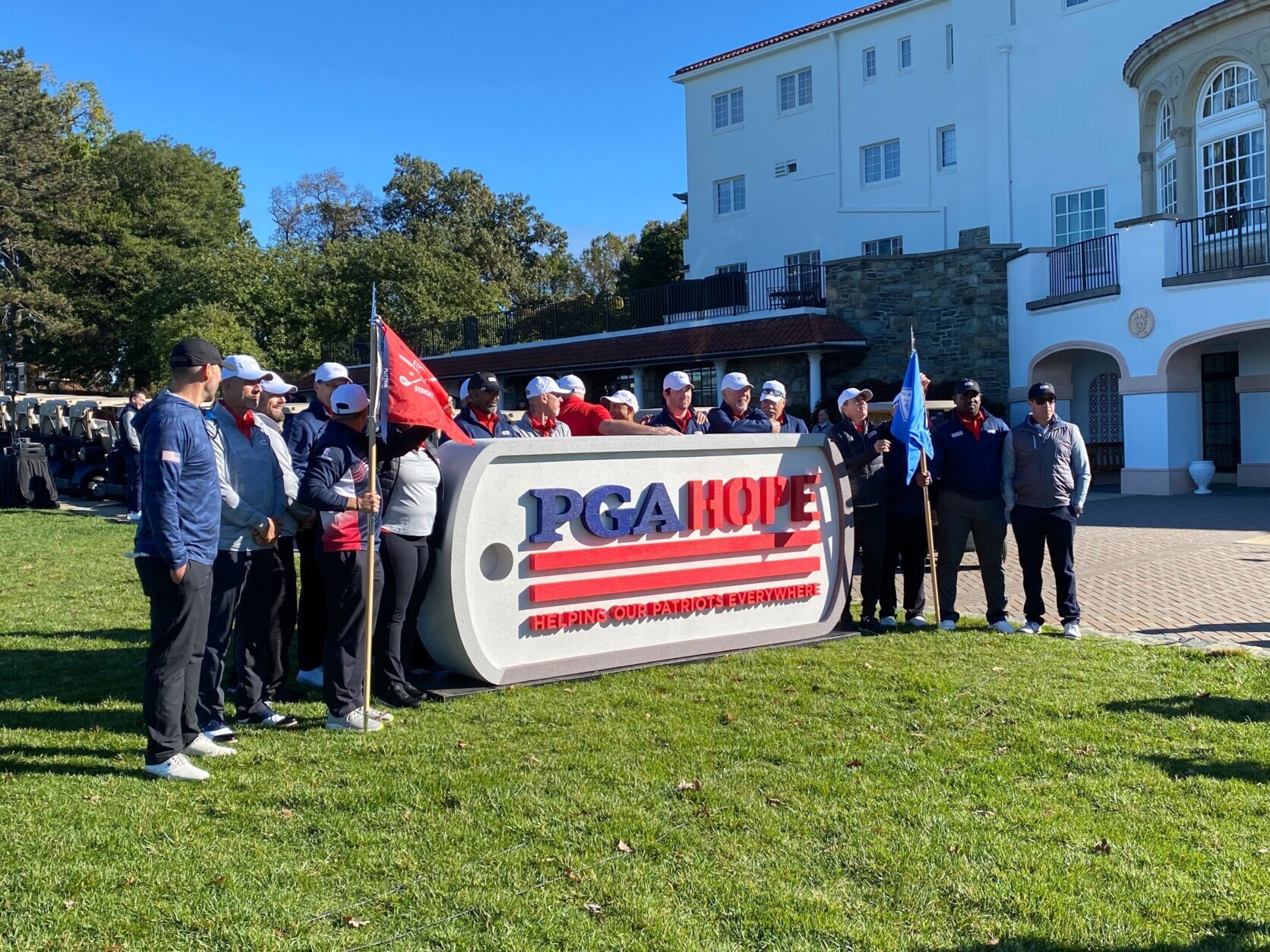 A group of people gathered in front of a sign that says "PGA HOPE"