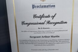 A proclamation from the U.S. House of Representatives sits inside a folder. Inside the paper's gold boarder, the proclamation reads: "Certificate of Congressional Recognition. Be it Known The office of Congressman Glenn Ivey recognizes the accomplishments and contribution to the community of: Sergeant Arthur Martin in recognition of his service in the United States Army Military Assistance Advisory Group and the 3rd Radio Research Unit during the Vietnam War. His commitment, courage, and leadership have contributed to the safety of our nation and serve as an inspiration for future generations. Presented on the sixth day of November 2023." The document is signed by Congressman Glenn F. Ivey, Representative of the 4th District of Maryland, in bold blue pen.