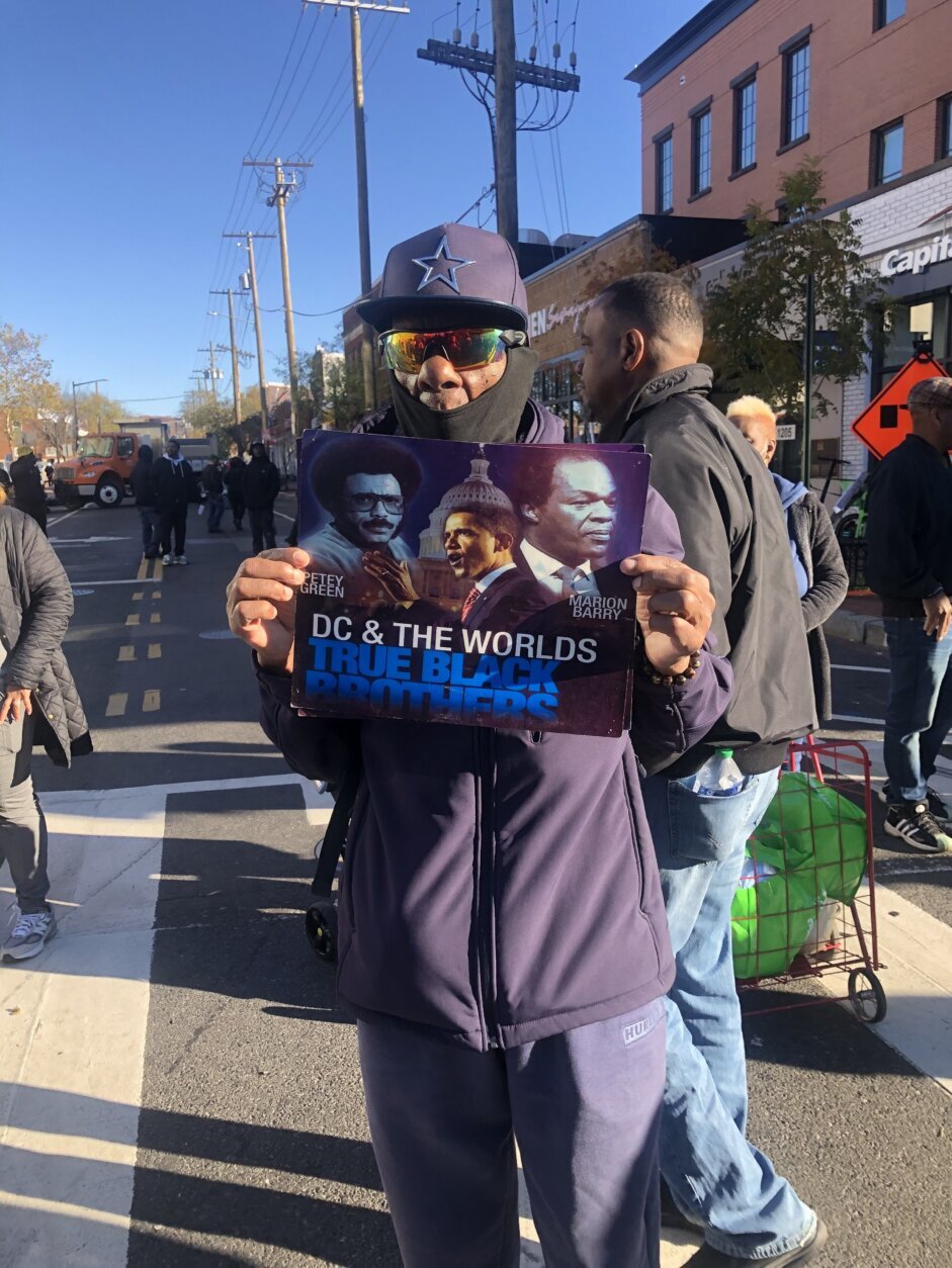 Man holding poster showing Petey Green, Barack Obama and Marion Barry