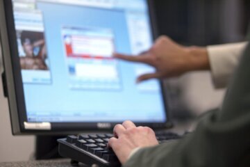 Person pointing at computer screen.