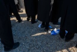 Orthodox Jewish protestors stand on an Israeli flag.