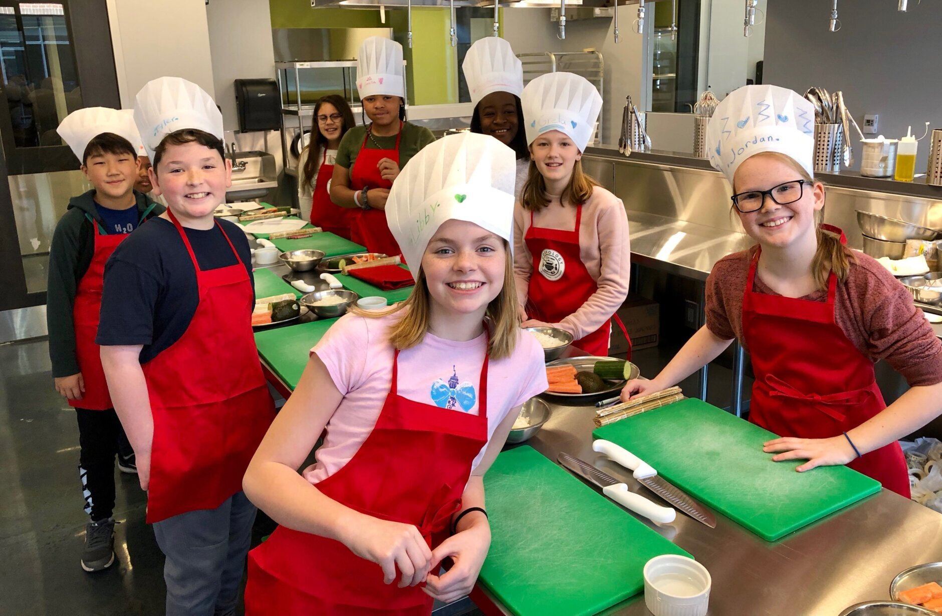 Kids wearing chef hats take a class at cookology