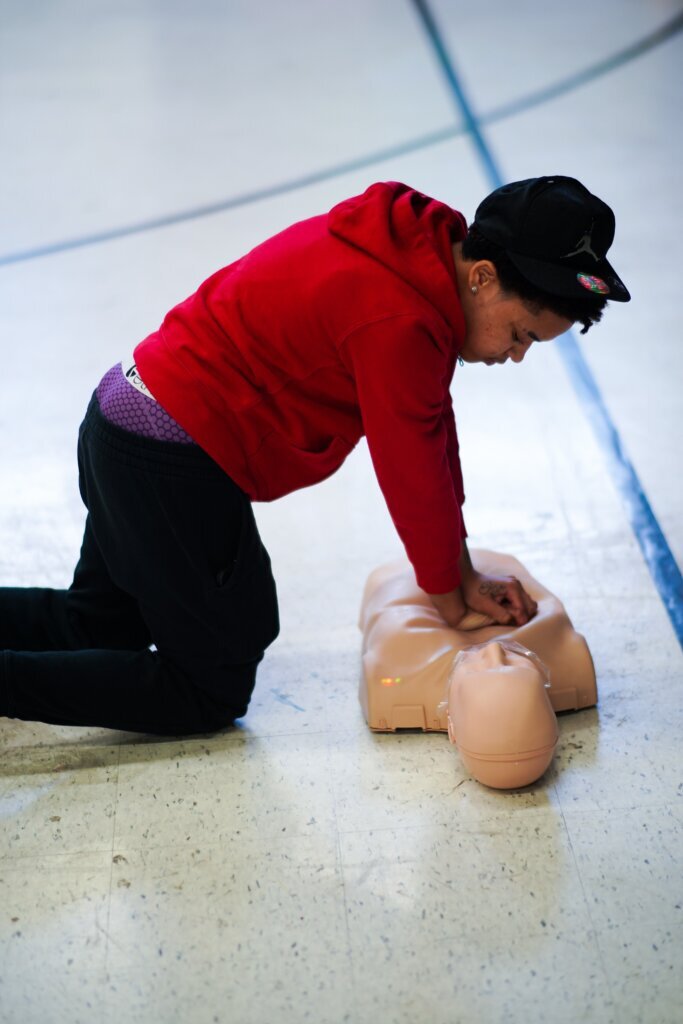 A young participant attempts CPR on a dummy