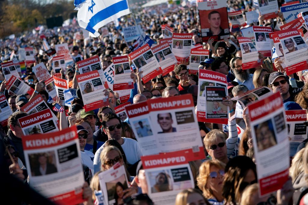 a crowd of demonstrators hold missing posters that seem to show photos of those kidnapped in Israel