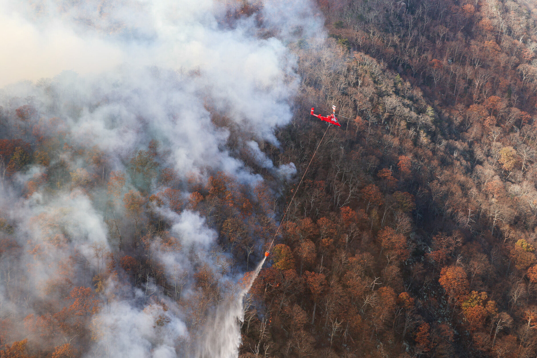 helicopter dropping water over forest fire in virginia