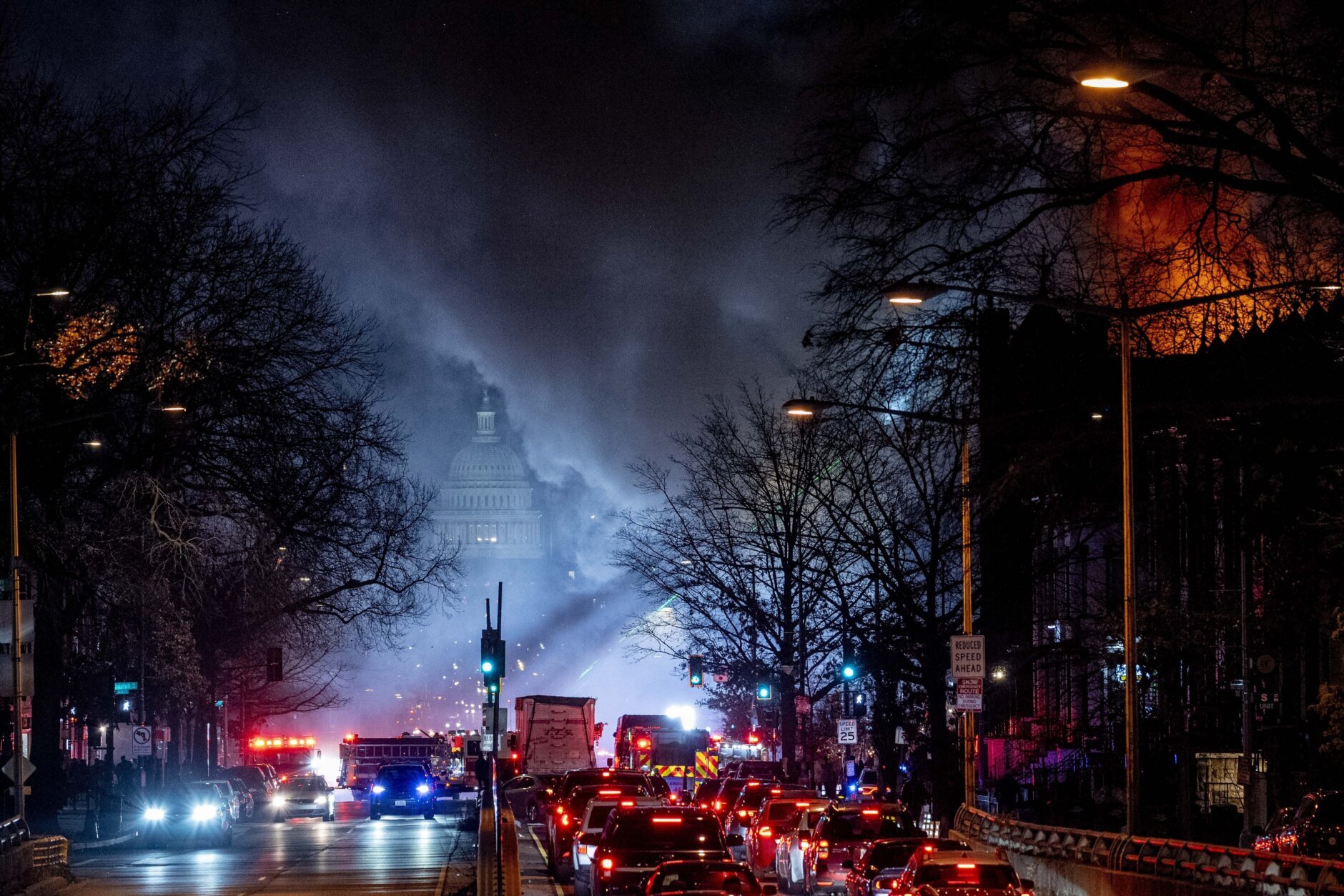 The Dome of the U.S. Capitol Building is visible through smoke, as flames shoot from a two alarm fire, at right, that started in a former fire station, Old Engine Company No. 12, now a landmark along North Capitol Street, in the Bloomingdale neighborhood of Washington, Friday, Dec. 15, 2023. (AP Photo/Andrew Harnik)