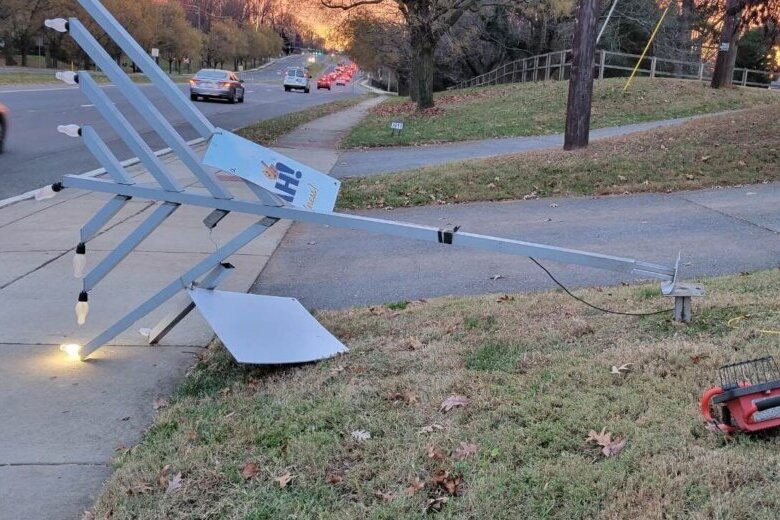 A large menorah is knocked on its side on the ground