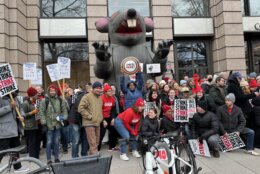 A group photo of strikers in front of an inflatable rat