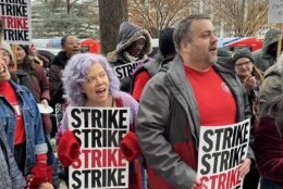 employees dressed in pops of red hold signs that say "strike"
