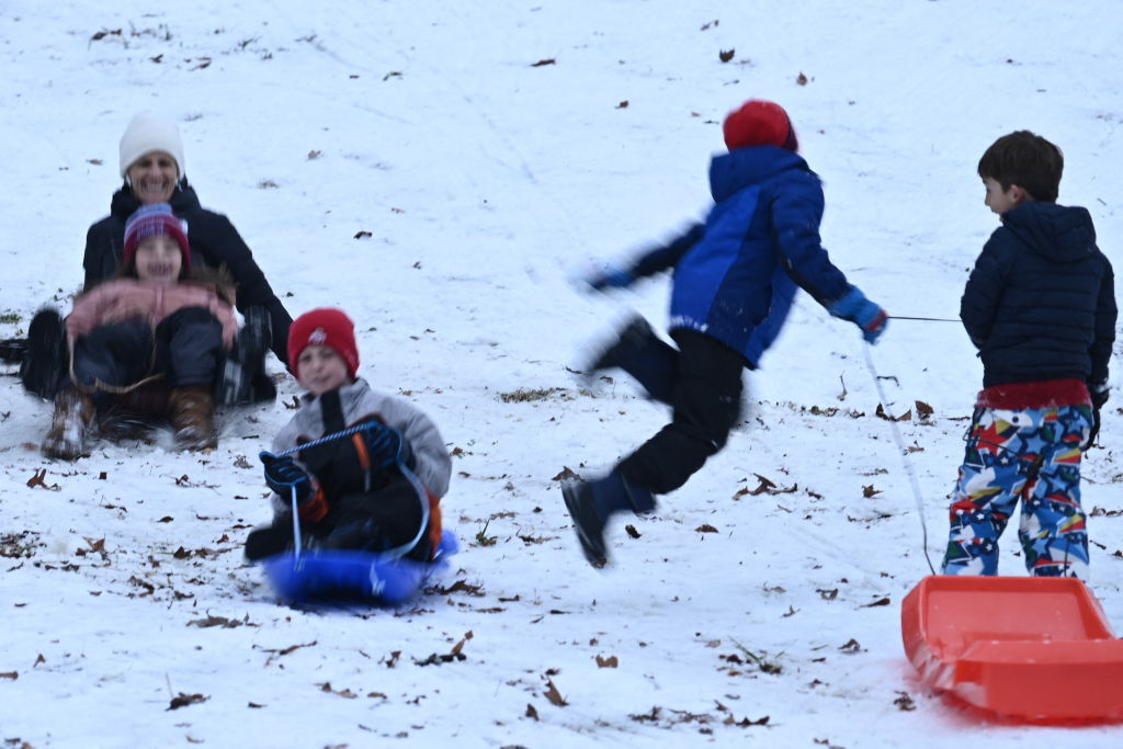 Children sled in the snow in Washington, DC, on January 16, 2024. The Washington DC metro region received between 2 and 4 inches of snow on January 15, 2024. (Photo by Brendan SMIALOWSKI / AFP) (Photo by BRENDAN SMIALOWSKI/AFP via Getty Images)