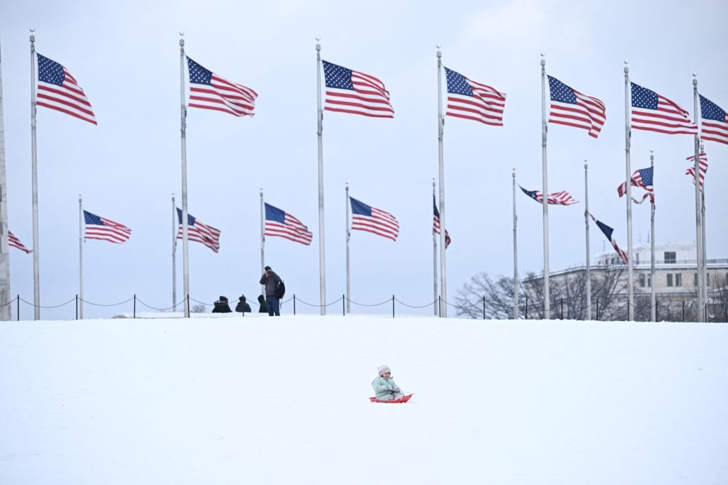 A child rides a sled near the Washington Monument in Washington, DC, on January 16, 2024. The Washington DC metro region received between 2 and 4 inches (5-10cm) of snow on January 15, 2024. (Photo by Brendan SMIALOWSKI / AFP) (Photo by BRENDAN SMIALOWSKI/AFP via Getty Images)