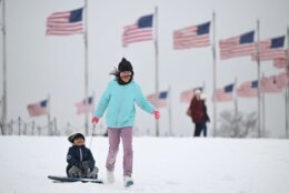 A girl pulls her brother on a sled at the Washington Monument on the National Mall in Washington, DC, on January 16, 2024. The Washington DC metro region received between 2 and 4 inches (5-10cm) of snow on January 15, 2024. (Photo by ANDREW CABALLERO-REYNOLDS / AFP) (Photo by ANDREW CABALLERO-REYNOLDS/AFP via Getty Images)
