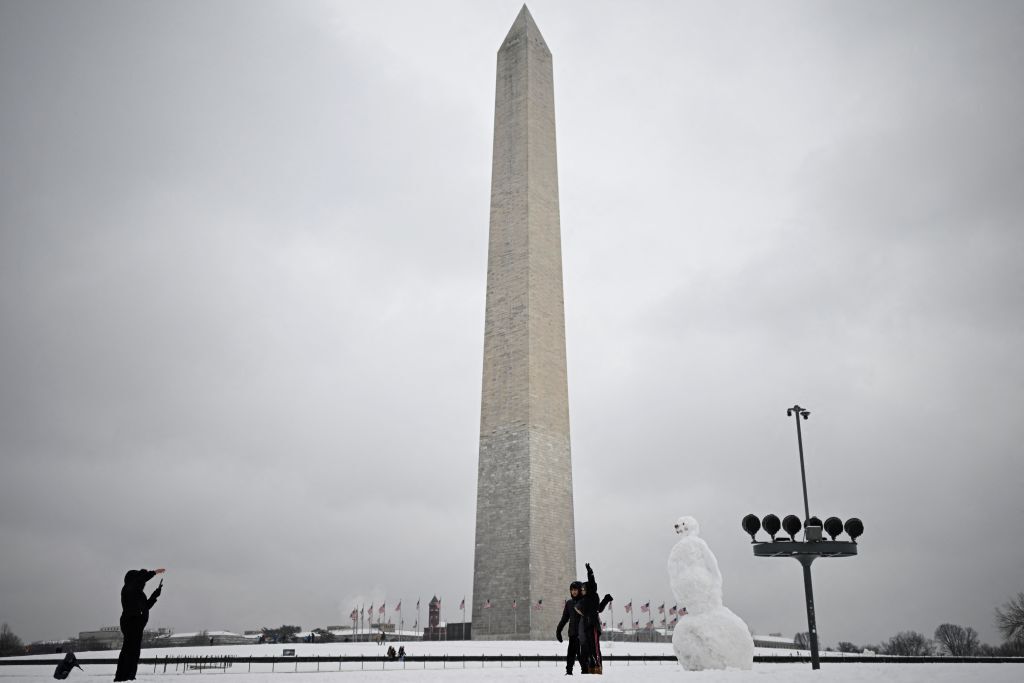 A family poses next to a snowman at the Washington Monument on the National Mall in Washington, DC, on January 16, 2024. The Washington DC metro region received between 2 and 4 inches (5-10cm) of snow on January 15, 2024. (Photo by ANDREW CABALLERO-REYNOLDS / AFP) (Photo by ANDREW CABALLERO-REYNOLDS/AFP via Getty Images)