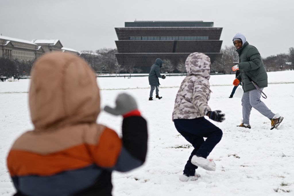 Denzel Box has a snowball fight with children near the African-American museum on the National Mall in Washington, DC, on January 16, 2024. The Washington DC metro region received between 2 and 4 inches (5-10cm) of snow on January 15, 2024. (Photo by ANDREW CABALLERO-REYNOLDS / AFP) (Photo by ANDREW CABALLERO-REYNOLDS/AFP via Getty Images)