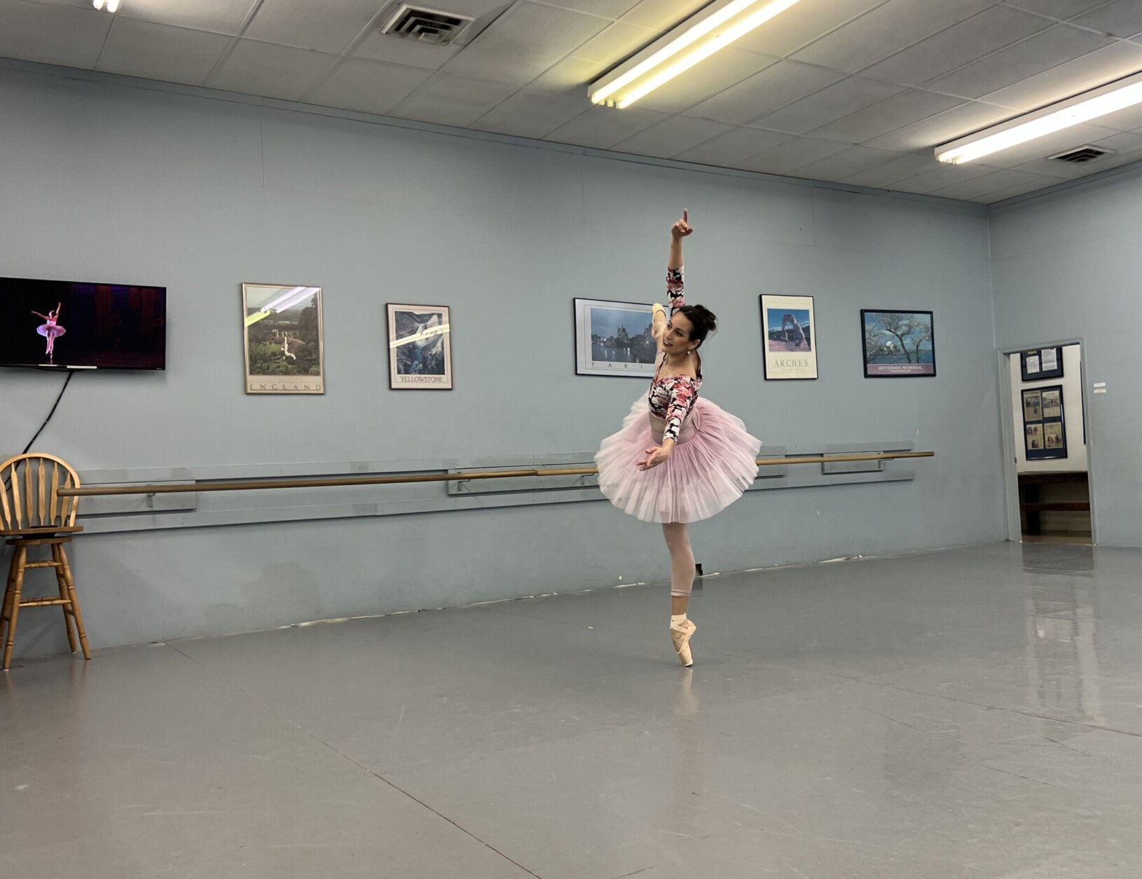 Moya performs a solo and stretches her leg toward the ceiling while balancing squarely on pointe.