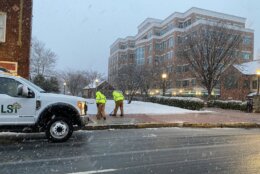 workers clean up slick sidewalks amid snowfall