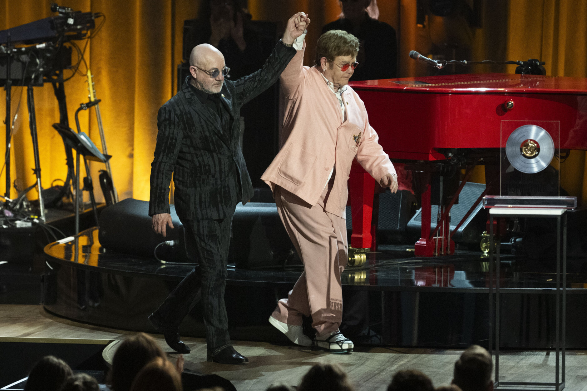 Bernie Taupin, left, and Elton John walk across the stage at the 2024 Library of Congress Gershwin Prize for Popular Song tribute concer honoring Elton John and Bernie Taupin on Wednesday, March 20, 2024 in Washington. (AP Photo/Kevin Wolf)