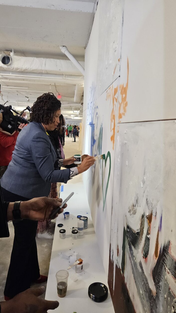 Muriel Bowser paints on a wall