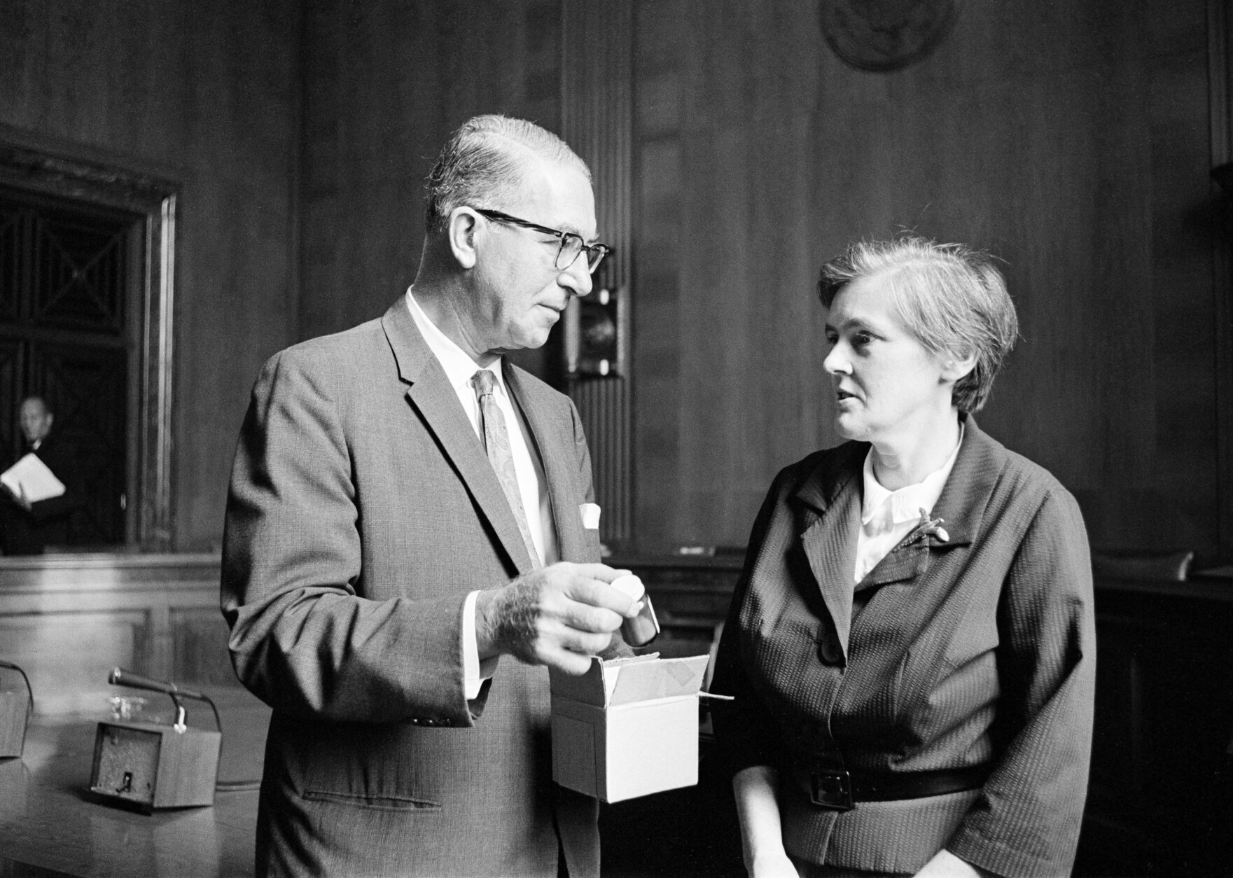 Sen. Estes Kefauver, D-Tenn., takes a bottle of thalidomide from a box as he talks with Dr. Frances Kelsey of the Food and Drug Administration, Aug. 6, 1962, in Washington. Dr. Kelsey met with the Senate judiciary Committee behind closed doors to testify in Washington on President Kennedy's proposed amendments to drug control legislation sponsored by Kefauver. (AP Photo/Henry Griffin)