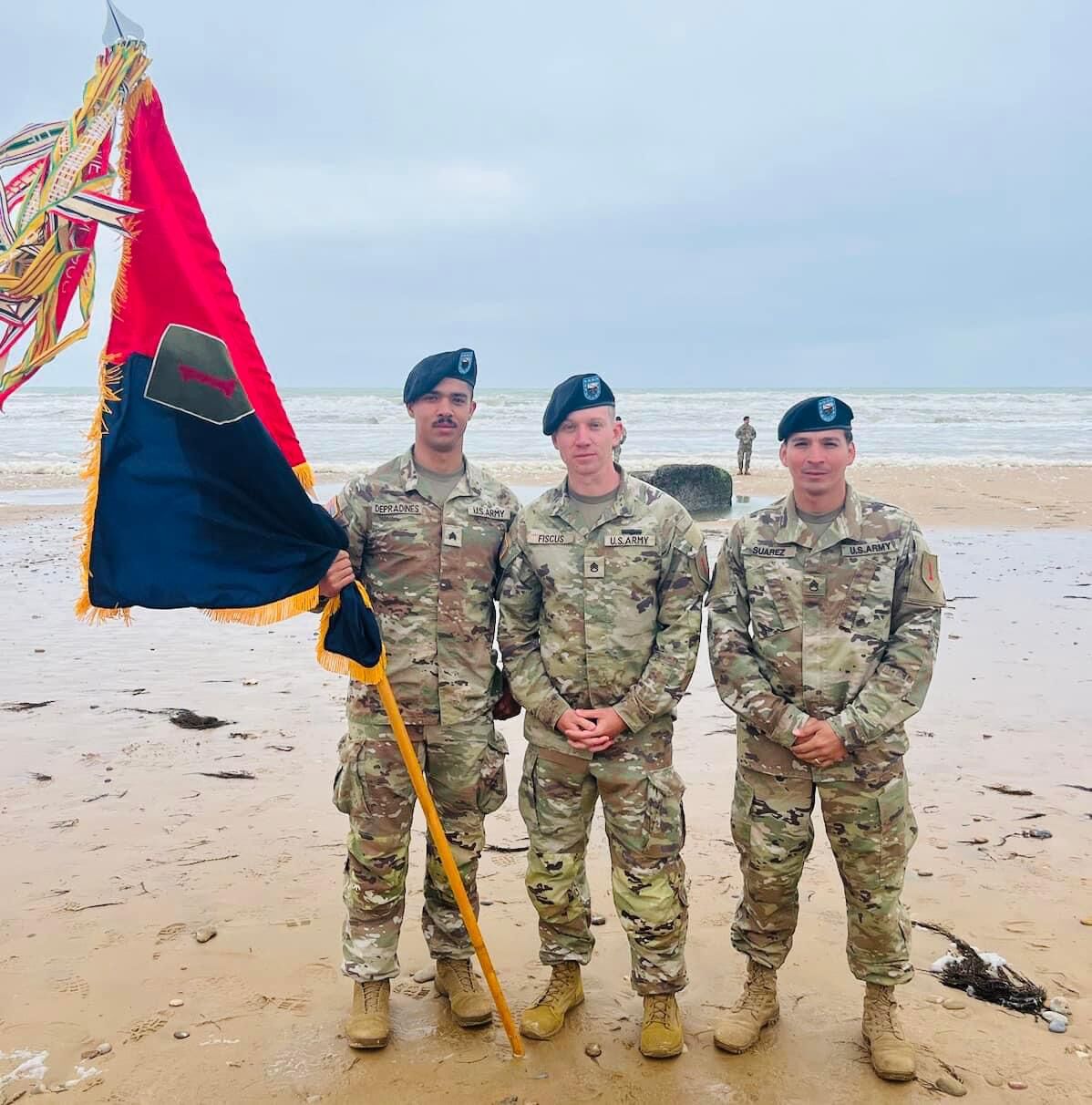U.S. Army Sgt. De Pradines holding a flag, next to two other soldiers