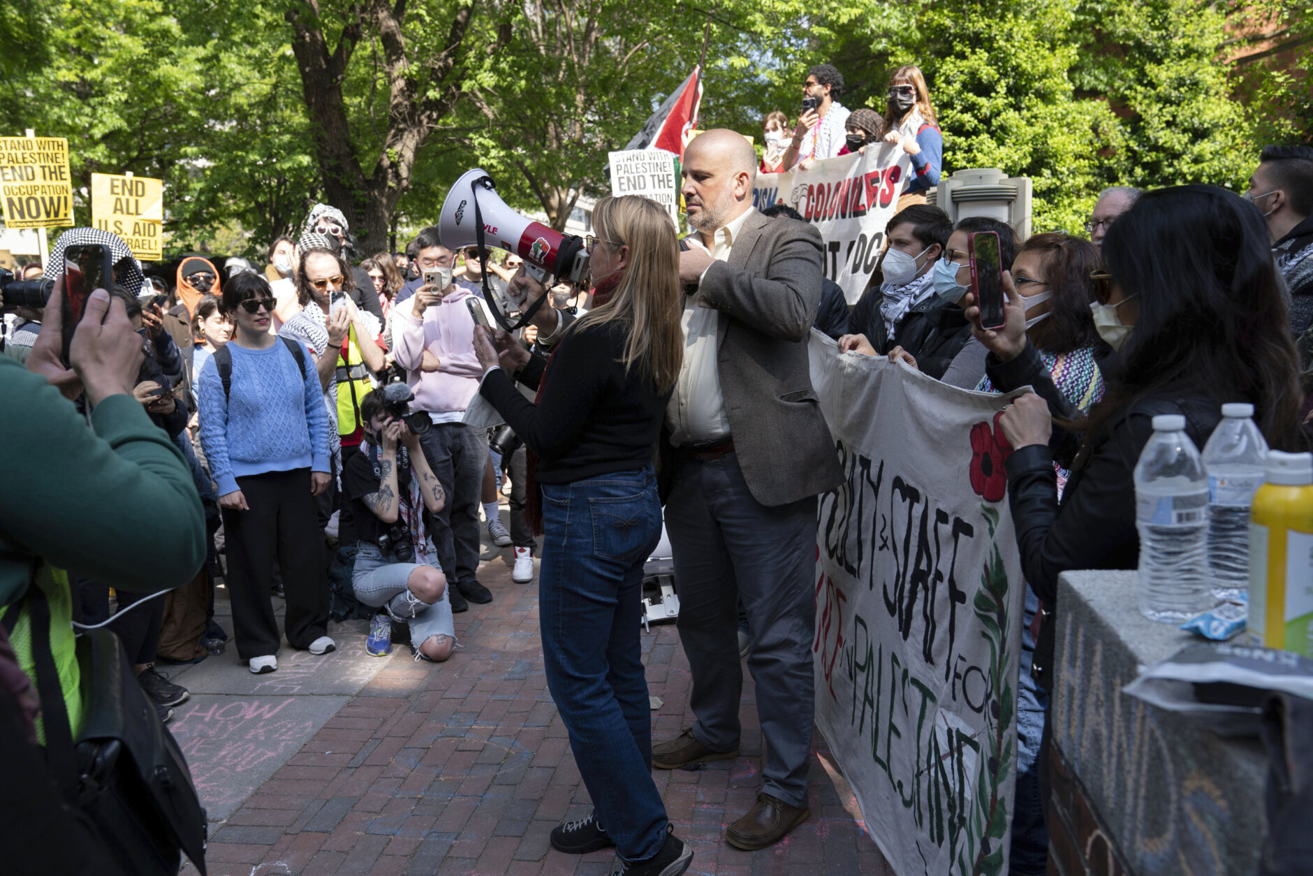 George Washington University faculty professors Will Youmans, center right, and Rochelle Davis, center left, lead a group of professors during a pro-Palestinian protest over the Israel-Hamas war on Friday, April 26, 2024, in Washington. (AP Photo/Jose Luis Magana)