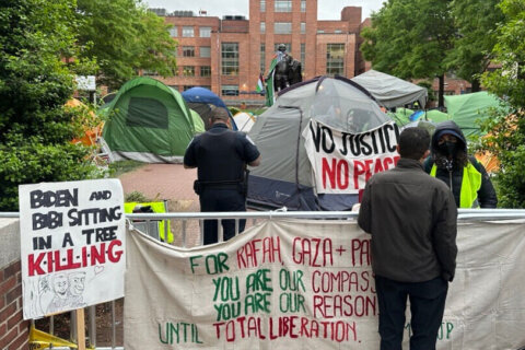 George Washington University police officers are seen scanning tents and signs