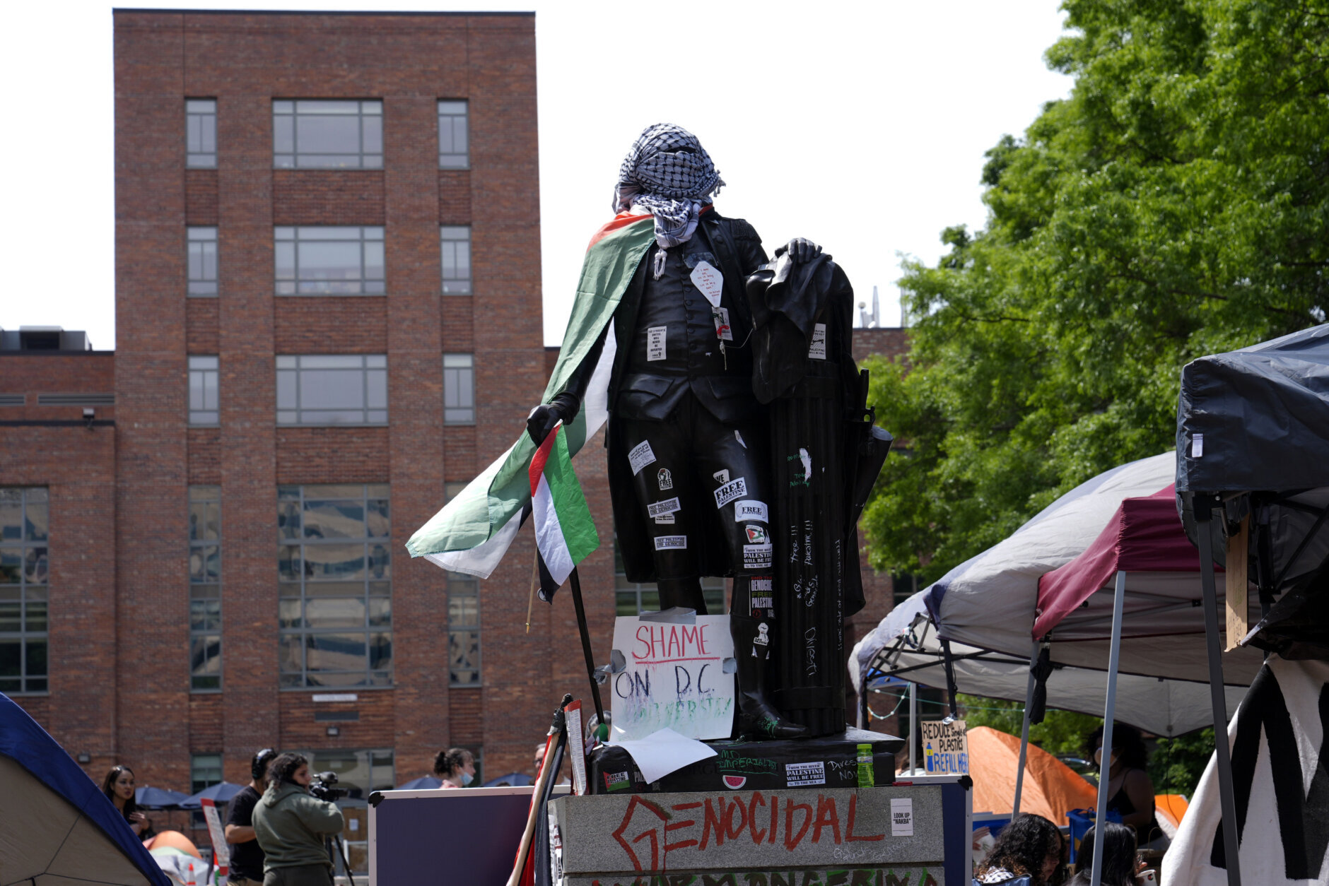 The statue of George Washington is covered in stickers, a Palestinian flag and a keffiyeh near a student encampment on the campus of George Washington University in Washington, Friday, May 3, 2024, as demonstrators protest the Israel-Hamas war. (AP Photo/Susan Walsh)