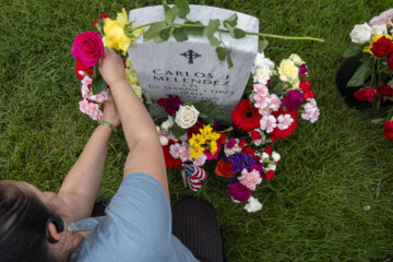 Ana Melendez, of Washington, whose family is originally from El Salvador, adorns the grave of her brother, Marine Corporal Carlos Melendez, who died serving in Iraq in 2011, in Section 60 of Arlington National Cemetery, Arlington, Va., Monday, May 27, 2024, on Memorial Day. "It's been so many years," says Melendez, "and it still feels like I am waiting for him to come home." (AP Photo/Jacquelyn Martin)