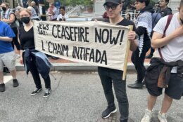 Demonstrators carry a sign that says "JEWS SAY: CEASEFIRE NOW! L'CHAIM INTIFADA".