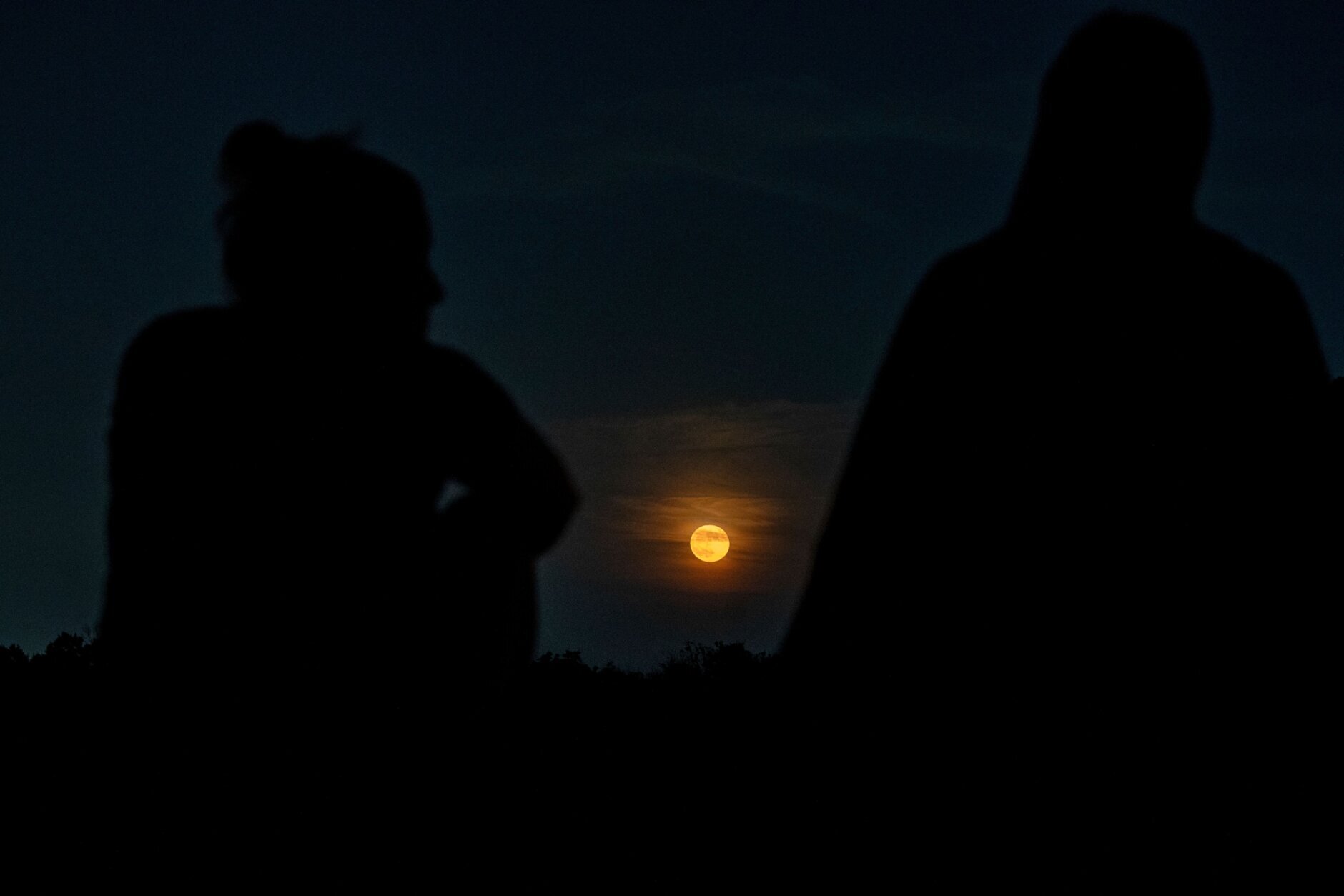 Onlookers watch as the full "Strawberry moon" rises in Arlington, Virginia, on June 14, 2022. (Photo by Stefani Reynolds / AFP) (Photo by STEFANI REYNOLDS/AFP via Getty Images)