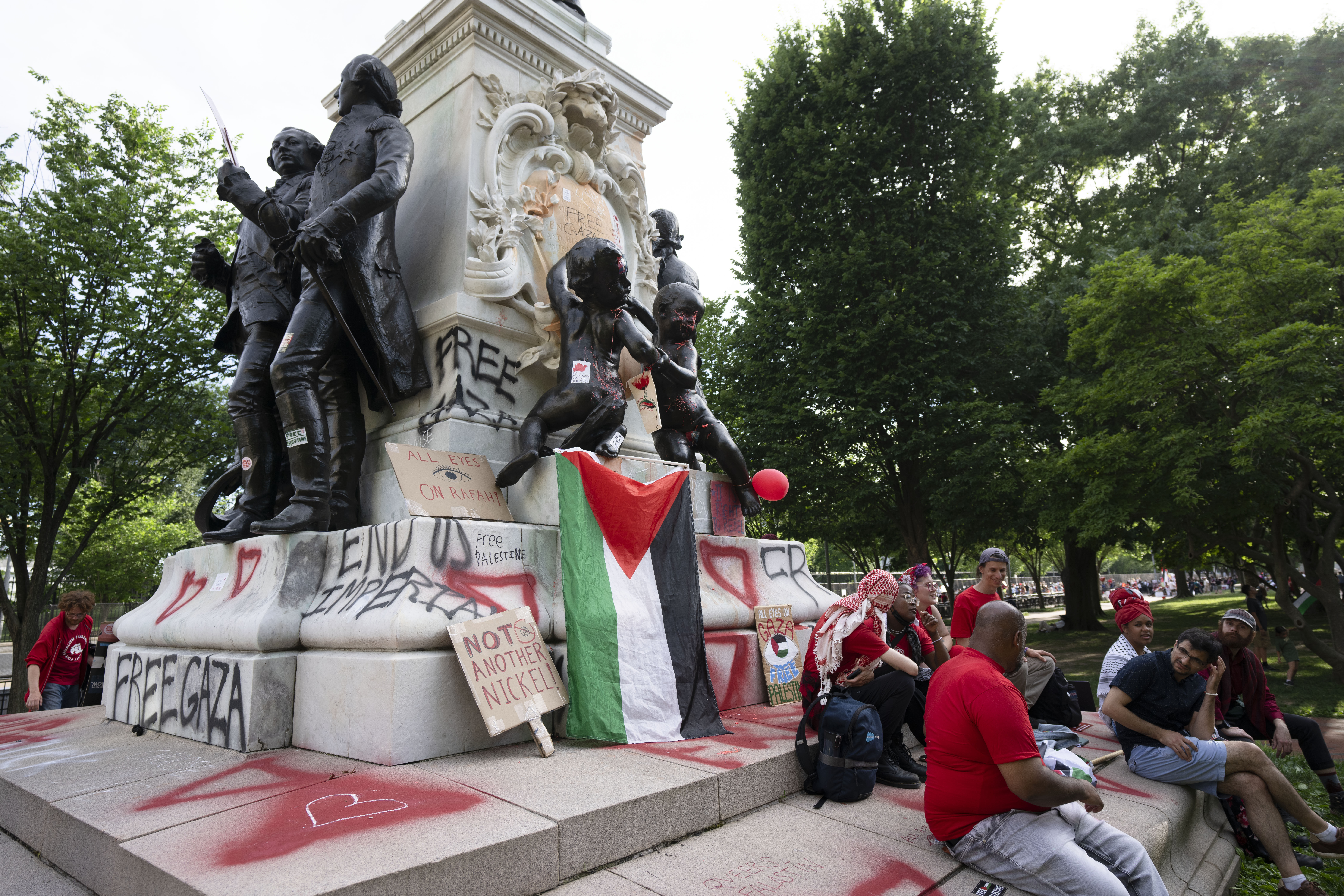 A group of protesters rest at the foot of the vandalized statue of French General Marquis de Lafayette as a pro-Palestinian rally ended in front of the White House in Washington, Saturday, June 8, 2024. (AP Photo/Manuel Balce Ceneta)