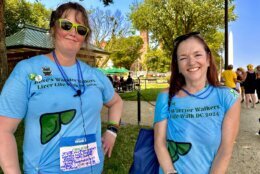 Two transplant survivor wearing blue t-shirts stand in front of a park space