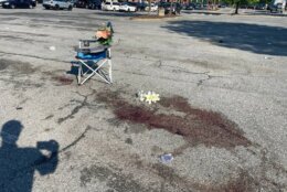 Flowers left near a blood-soaked patch of pavement in the shopping center parking lot where the shooting took place. (WTOP/Kyle Cooper)