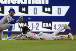 Washington Nationals' James Wood, right, slides safely into second base after a throwing error at first as New York Mets shortstop Francisco Lindor, left, waits for the throw during the ninth inning of a baseball game at Nationals Park, Monday, July 1, 2024, in Washington. (AP Photo/Alex Brandon)