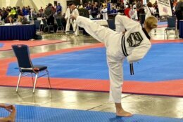 In an action shot, Kelley kicks the air, her back visible as a distant crowd watches.