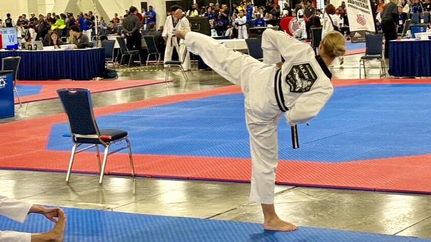 In an action shot, Kelley kicks the air, her back visible as a distant crowd watches.