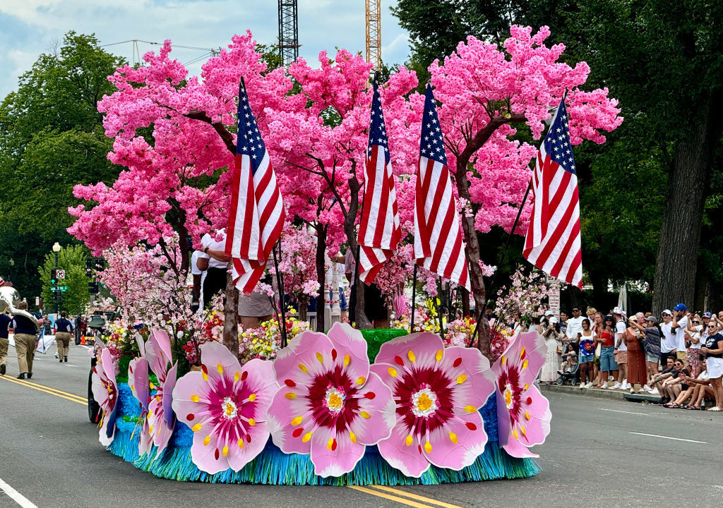 a parade float with large cherry blossom flower cutouts and faux trees along with American flags