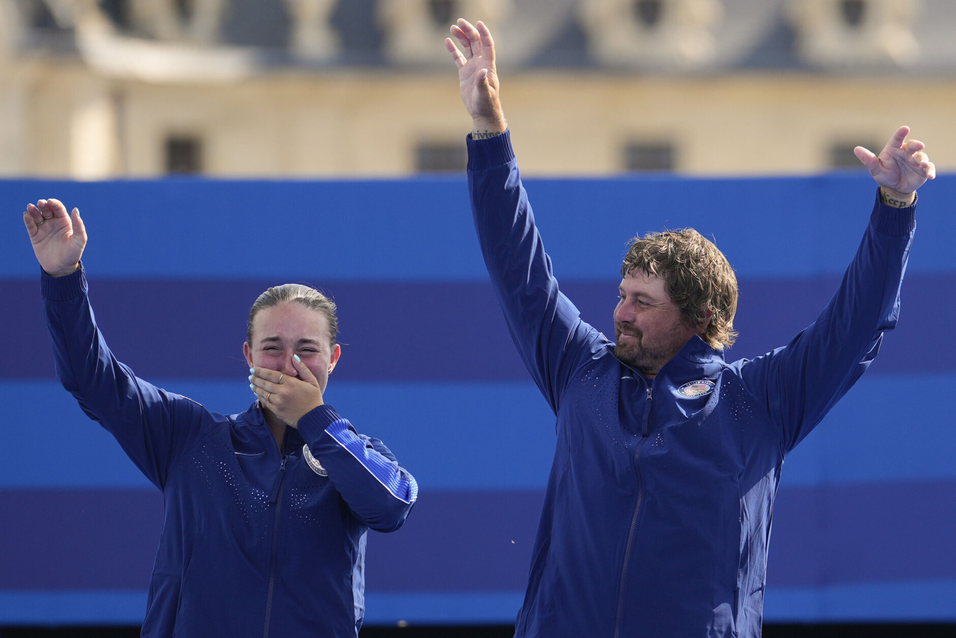 Bronze medal winners, Casey Kaufhold and Brady Ellison of the United States wave from the podium after the Archery mixed team finals at the 2024 Summer Olympics, Friday, Aug. 2, 2024, in Paris, France. (AP Photo/Brynn Anderson)
