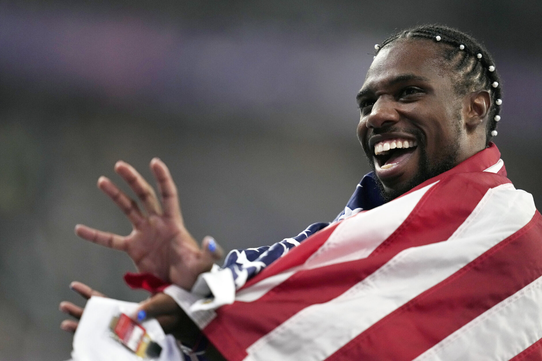 Noah Lyles, of the United States, celebrates after winning the gold medal in in the men's 100 meters final at the 2024 Summer Olympics, Sunday, Aug. 4, 2024, in Saint-Denis, France. (AP Photo/Ashley Landis)