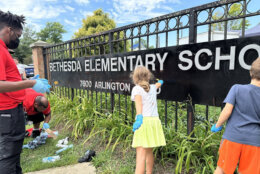 People cleaning anti-Israel and antisemitic graffiti from an elementary school sign.