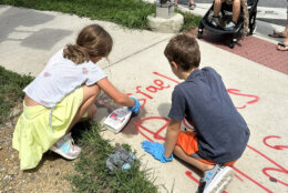 Children cleaning anti-Israel and antisemitic graffiti from a sidewalk.